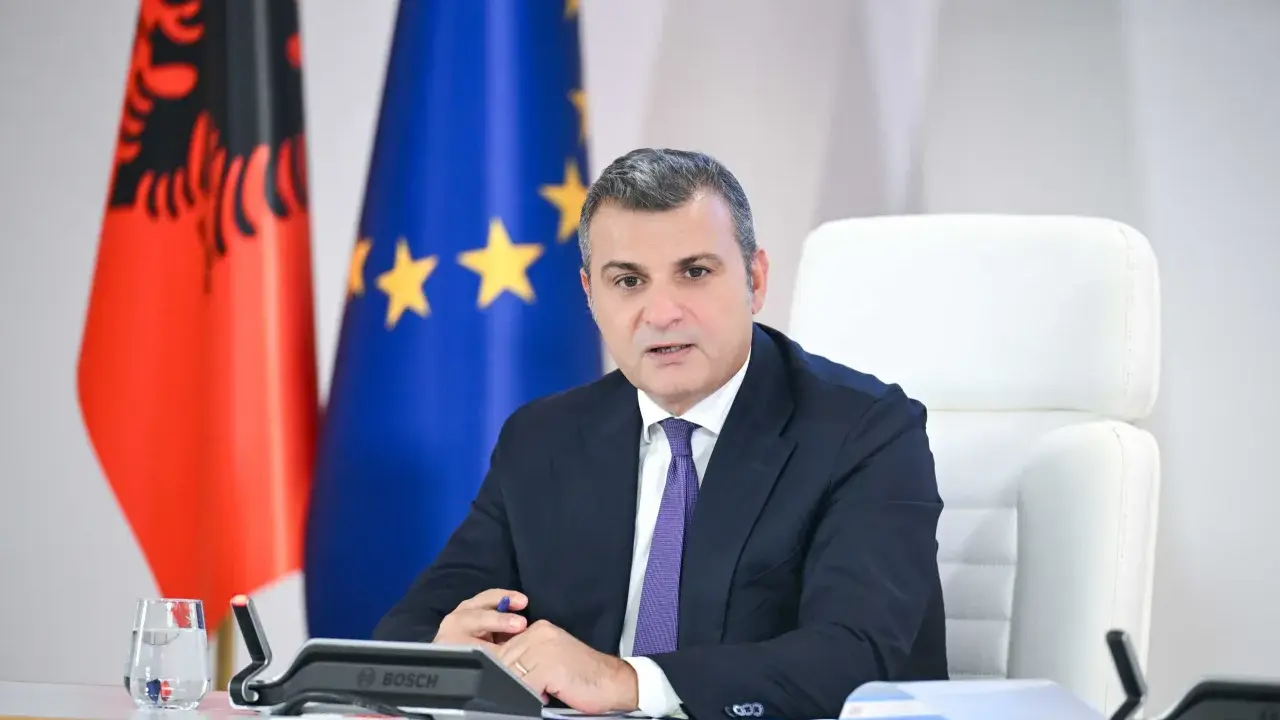 Governatore della **Bank of Albania** in riunione, con le bandiere albanese ed europea sullo sfondo.