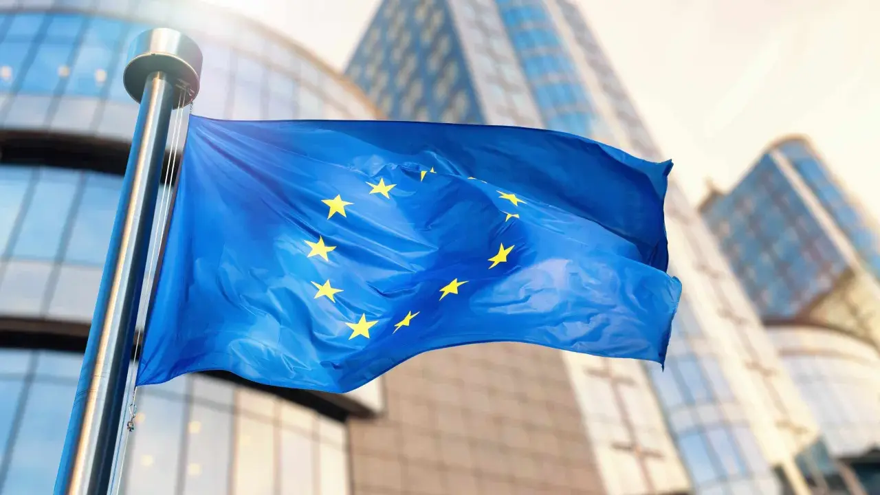 Bandiera europea sventola davanti a edifici moderni, simbolo di unità e di un futuro con un **grant significato economia** per il continente.