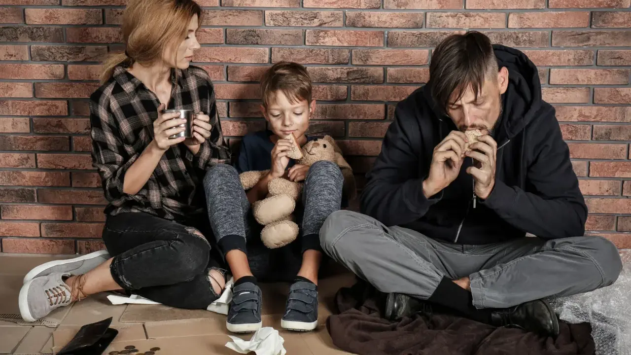 Famiglia seduta a terra, con poco cibo, vicina alla soglia di povertà.