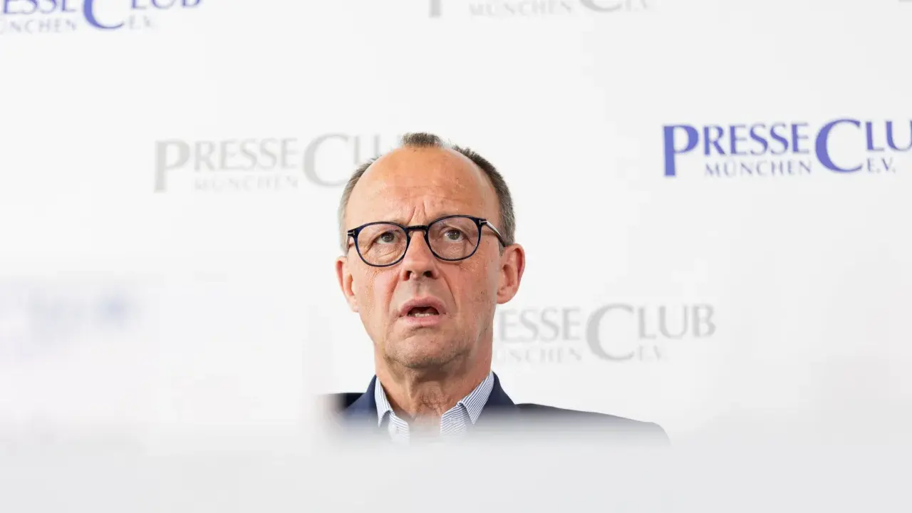 Olaf Scholz, cancelliere tedesco dopo Merkel, parla con espressione seria davanti a uno sfondo con il logo "Presse Club München".