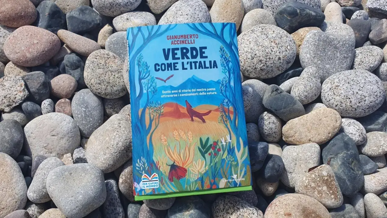 Il libro verde "Verde come l'Italia" giace tra ciottoli levigati, con un'illustrazione di natura e animali.