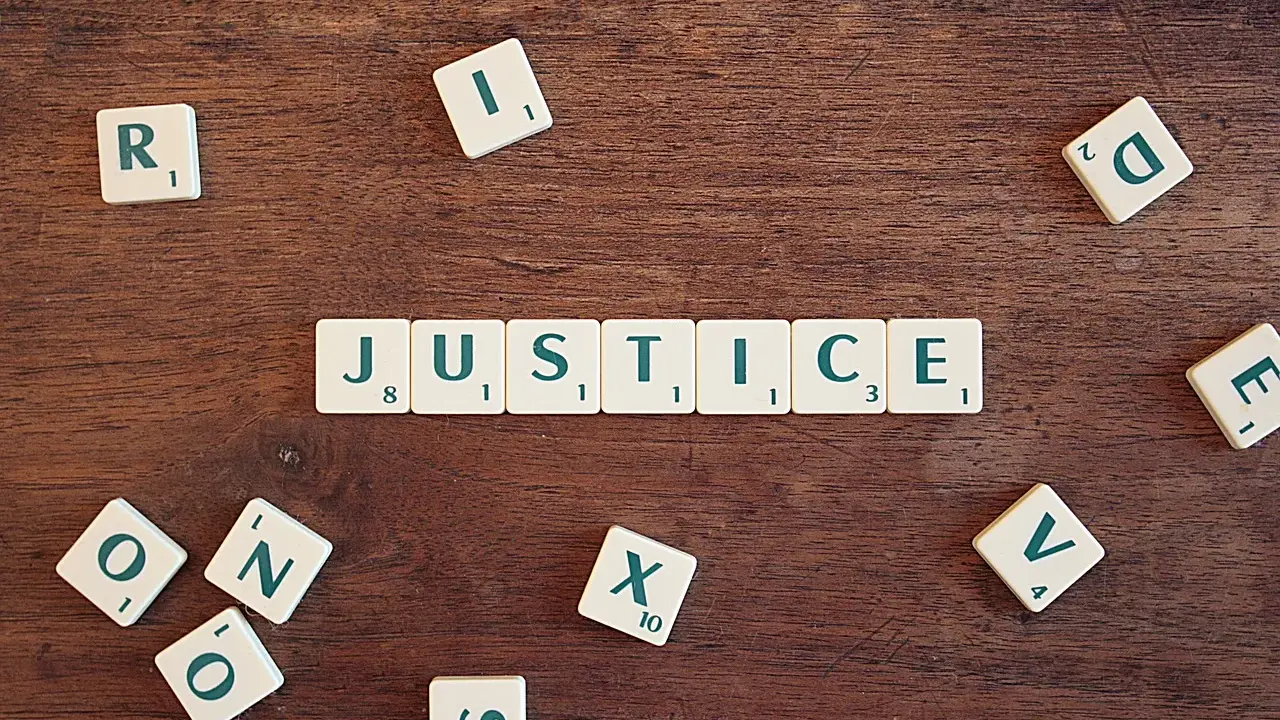 Tessere del gioco compongono la parola "JUSTICE", evocando il suo significato legale e morale.