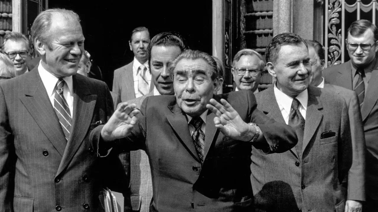 Leader sovietico Leonid Breznev, con le mani alzate, durante l'atto finale di Helsinki. Accanto a lui, Gerald Ford sorride.