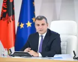 Governatore della **Bank of Albania** in riunione, con le bandiere albanese ed europea sullo sfondo.