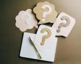 Penne e quaderno aperto, circondati da fumetti con punti interrogativi. Un invito a fare domande, con la promessa di patrocinio gratuito.