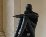Statua di una figura che legge, con un libro aperto. La scena evoca il profondo significato della conoscenza e della lettura, una vera glossa significato.