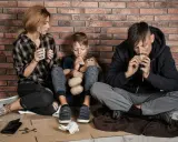 Famiglia seduta a terra, con poco cibo, vicina alla soglia di povertà.