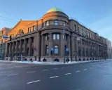 Edificio imponente con colonne, cupola verde e bandiere lituane. Il **bank of Lithuania** si erge maestoso sotto un cielo azzurro.