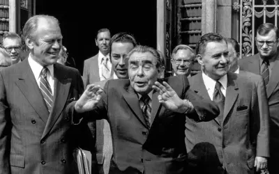 Leader sovietico Leonid Breznev, con le mani alzate, durante l'atto finale di Helsinki. Accanto a lui, Gerald Ford sorride.