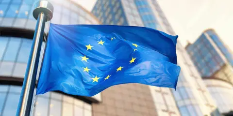 Bandiera europea sventola davanti a edifici moderni, simbolo di unità e di un futuro con un **grant significato economia** per il continente.