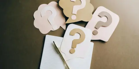 Penne e quaderno aperto, circondati da fumetti con punti interrogativi. Un invito a fare domande, con la promessa di patrocinio gratuito.