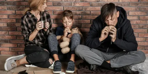 Famiglia seduta a terra, con poco cibo, vicina alla soglia di povertà.