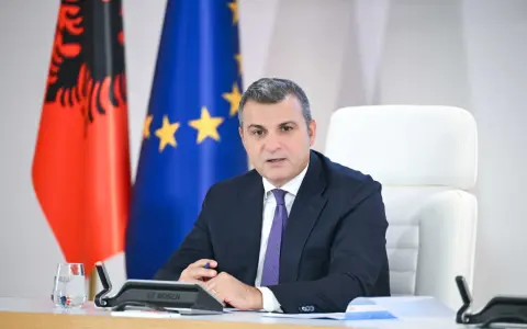 Governatore della **Bank of Albania** in riunione, con le bandiere albanese ed europea sullo sfondo.