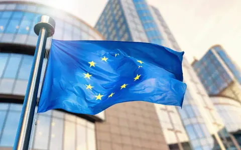 Bandiera europea sventola davanti a edifici moderni, simbolo di unità e di un futuro con un **grant significato economia** per il continente.