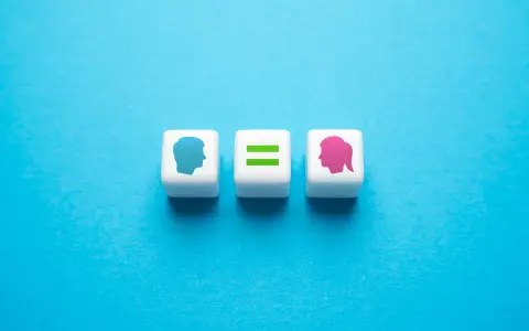 Tre cubi bianchi su sfondo blu. Uno mostra un profilo maschile blu, un altro un segno di uguale verde, e l'ultimo un profilo femminile rosa. Rappresentano l'equità significato.