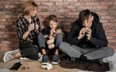 Famiglia seduta a terra, con poco cibo, vicina alla soglia di povertà.