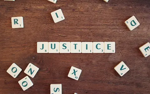 Tessere del gioco compongono la parola "JUSTICE", evocando il suo significato legale e morale.