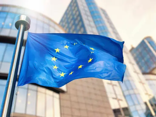 Bandiera europea sventola davanti a edifici moderni, simbolo di unità e di un futuro con un **grant significato economia** per il continente.