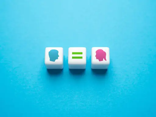 Tre cubi bianchi su sfondo blu. Uno mostra un profilo maschile blu, un altro un segno di uguale verde, e l'ultimo un profilo femminile rosa. Rappresentano l'equità significato.