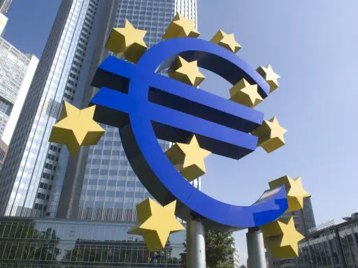 Simbolo dell'Euro con stelle gialle davanti a grattacieli moderni, evocando la stabilità della politica fiscale europea.