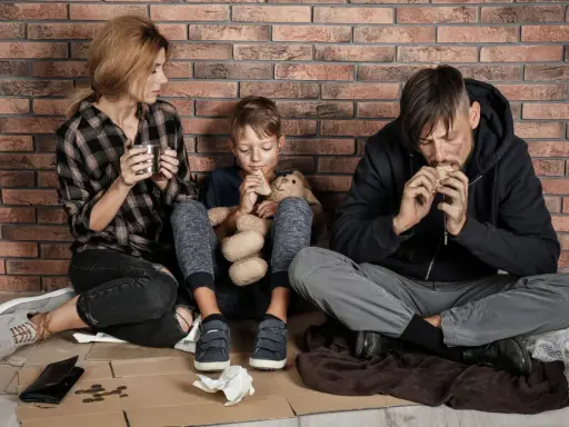 Famiglia seduta a terra, con poco cibo, vicina alla soglia di povertà.