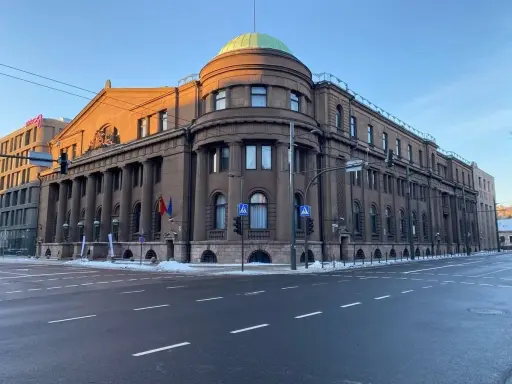 Edificio imponente con colonne, cupola verde e bandiere lituane. Il **bank of Lithuania** si erge maestoso sotto un cielo azzurro.