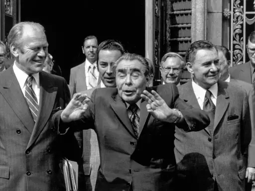 Leader sovietico Leonid Breznev, con le mani alzate, durante l'atto finale di Helsinki. Accanto a lui, Gerald Ford sorride.