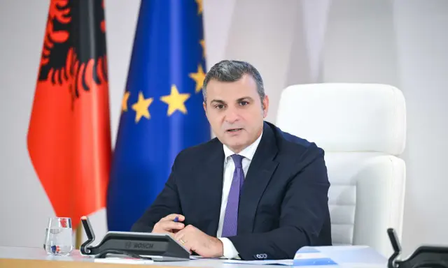 Governatore della **Bank of Albania** in riunione, con le bandiere albanese ed europea sullo sfondo.