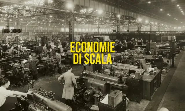 Operai in una grande fabbrica lavorano a macchine utensili, un esempio di economie di scala nella produzione industriale.