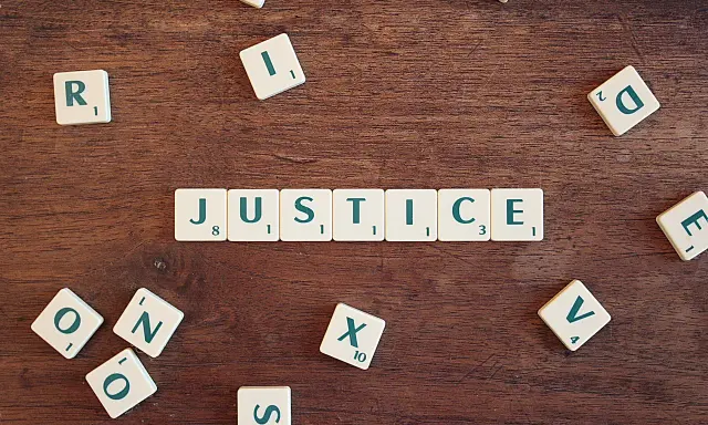 Tessere del gioco compongono la parola "JUSTICE", evocando il suo significato legale e morale.