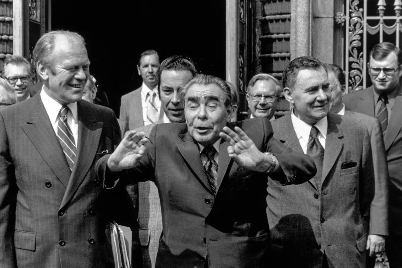 Leader sovietico Leonid Breznev, con le mani alzate, durante l'atto finale di Helsinki. Accanto a lui, Gerald Ford sorride.