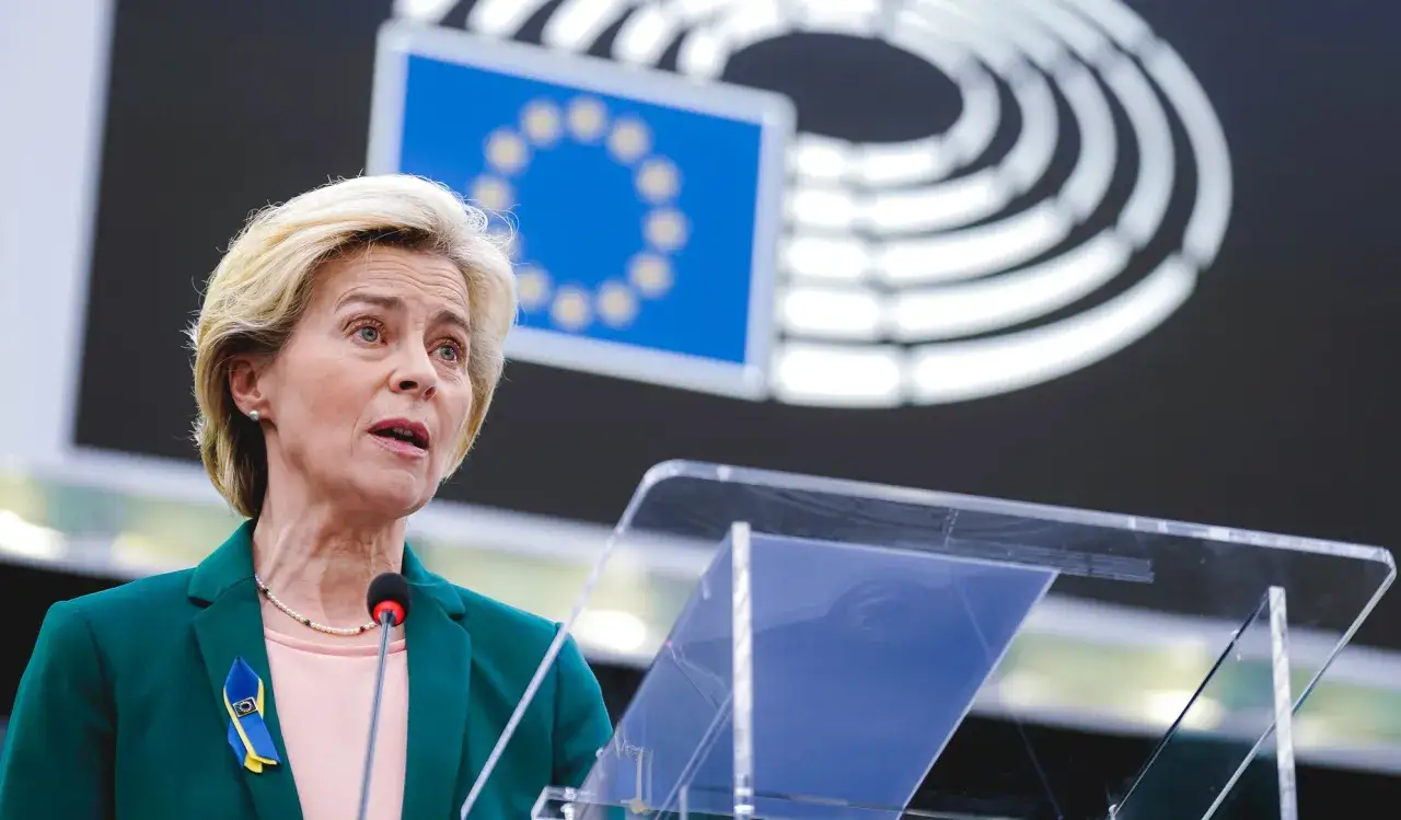 Ursula von der Leyen parla del futuro della politica fiscale europea, con la bandiera UE sullo sfondo.