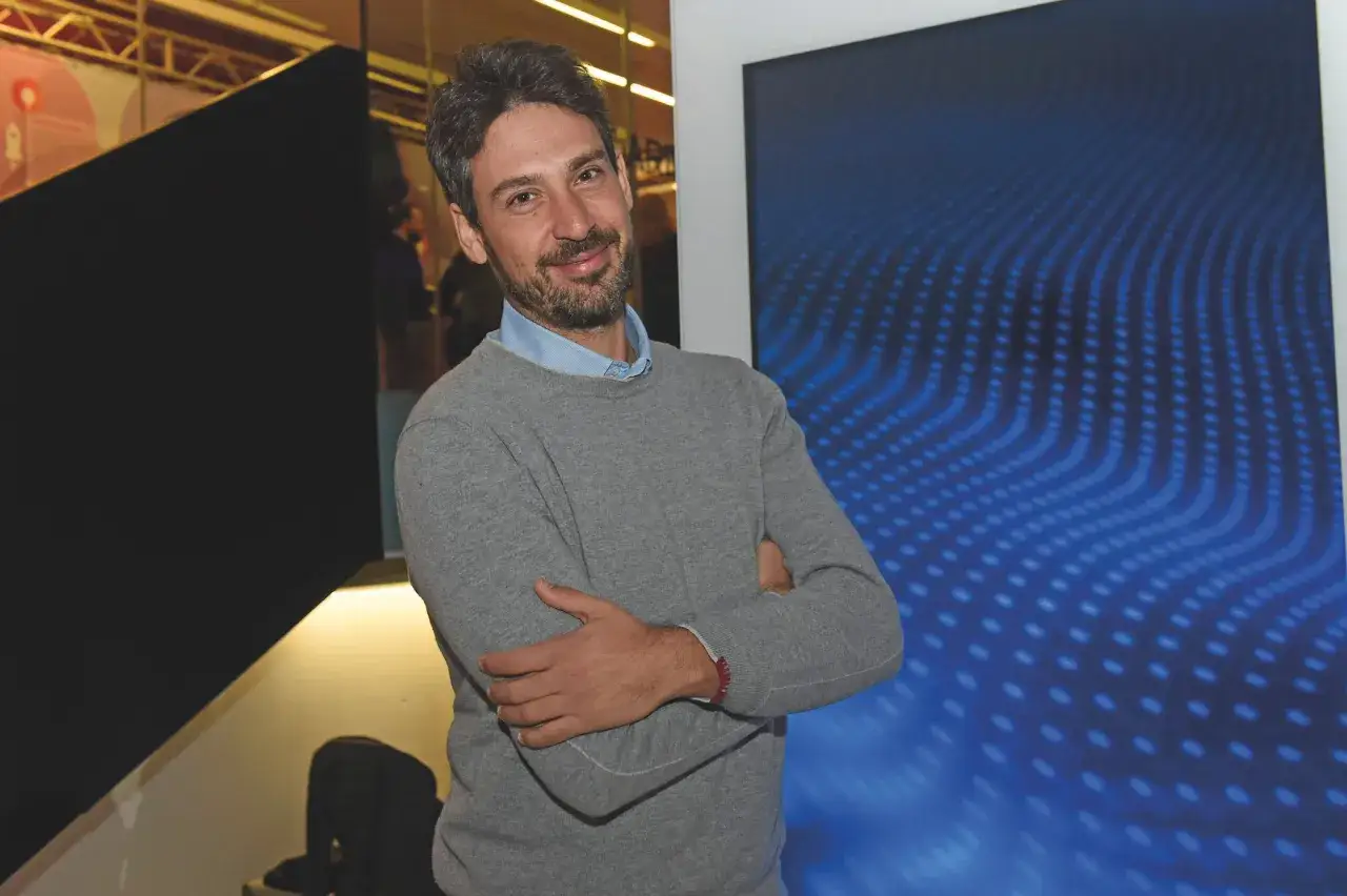 Uomo sorridente con braccia conserte, un vero imprenditore significato di successo, con sfondo blu astratto.