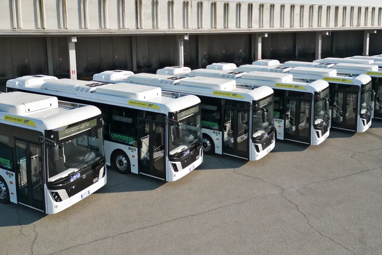 Flotta di autobus bianchi parcheggiati, pronti per il servizio. Le imprese pubbliche come GTT garantiscono la mobilità.