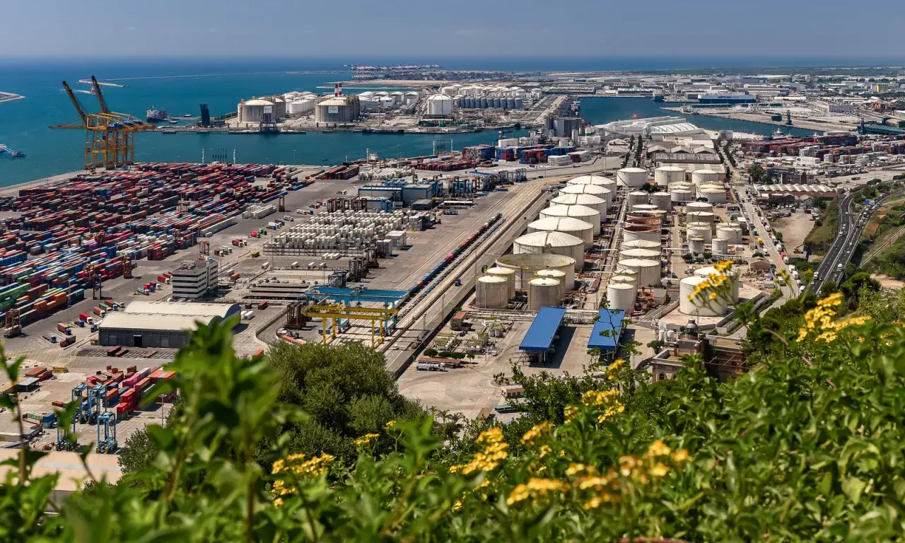 Vasta area portuale con container, serbatoi e gru. Un esempio di come funziona il porto franco cosa significa per il commercio.